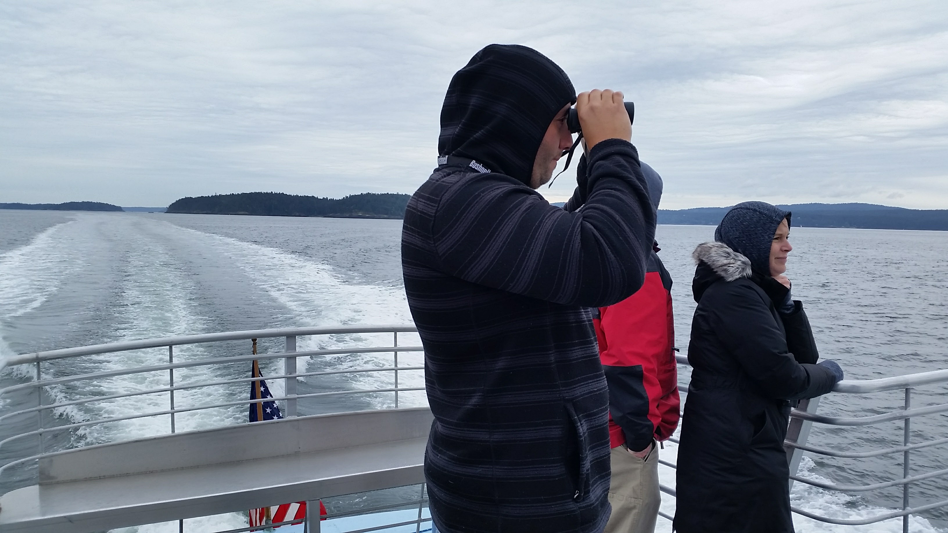 My husband using binoculars on the back of the whale watch boat looking for whales